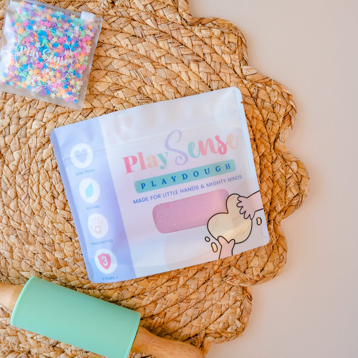 Play dough set with a rolling pin and confetti on a woven mat